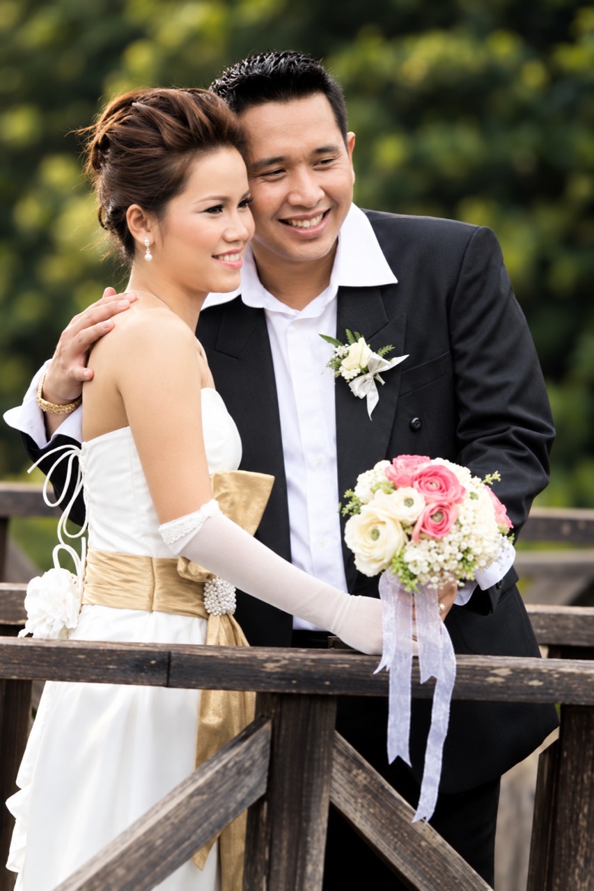 Reinheart dan Rima mengenakan busana pengantin, berpelukan di jembatan kayu