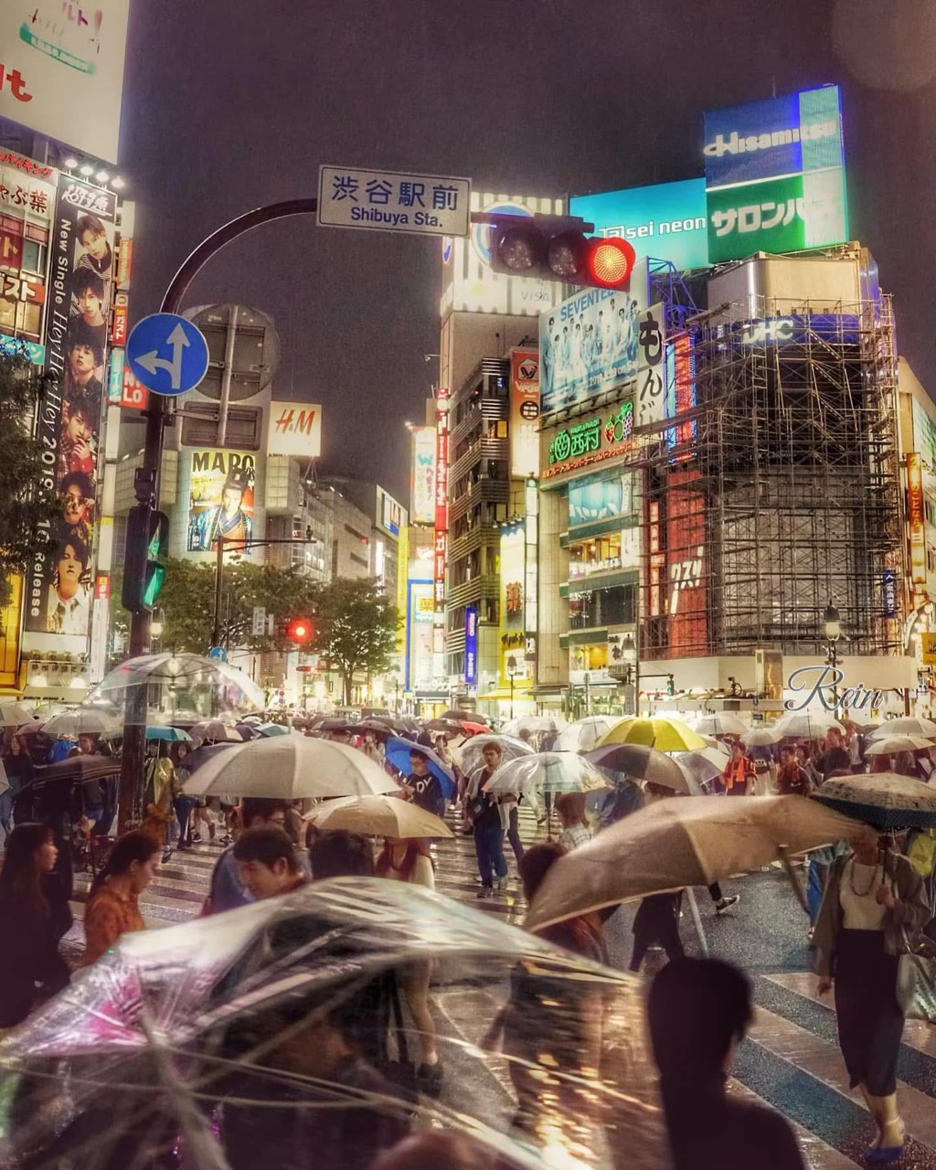 Kerumunan berpayung di Shibuya pada malam yang hujan