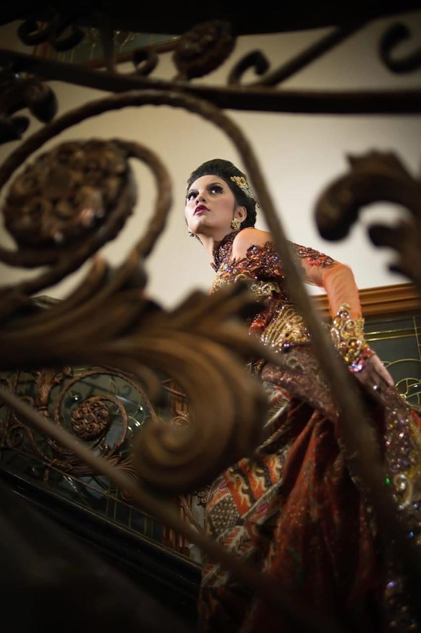 Potret perempuan di antara ornamen merah dan emas